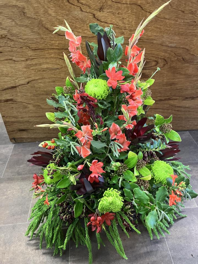 Flame Arrangement - A striking front-facing arrangement in vibrant coral, burgundy and fresh green tones, expertly handcrafted with seasonal flowers and foliage.
