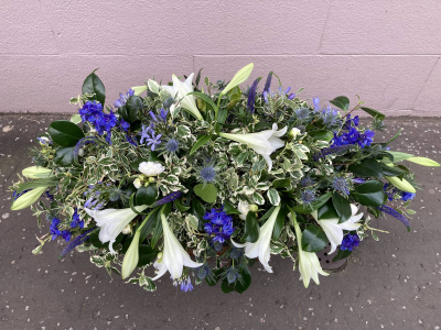 Blue & White Casket Spray - A graceful casket spray in crisp white and rich blue tones, handcrafted with seasonal flowers and foliage to create a peaceful and elegant tribute.