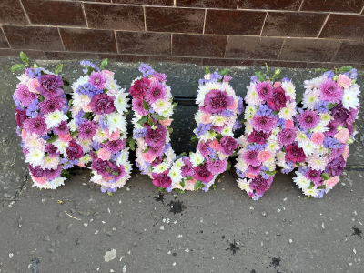 Pastel Letter Tribute - A handcrafted floral letter tribute in soft pink, lilac and white tones, created with seasonal flowers for a personal and meaningful farewell.